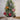 Small decorated Christmas tree with animal-themed ornaments against a softly blurred light background