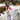 Person holding a mug with a cat and a small dog figure on a fluffy surface with Christmas trees in the background.