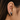 Black cat-shaped earrings worn on an ear with dark hair.