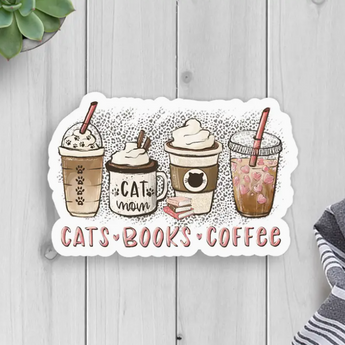A sticker featuring four coffee cups with cat-themed designs and the words "Cats Books Coffee" in light pink, separated by pink hearts.