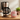 A pink ceramic coffee mug with a cute cartoon cat face and red hearts, set on a wooden countertop next to a coffee maker, coffee beans, and a jar of sugar.