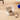 Cat-shaped ceramic bowl with pet food on a wooden floor, next to a blue ball and a small mouse toy.