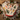 Two Christmas-themed oven mitts with a cream background and a festive print of cats, Christmas trees, candy canes, and bells, arranged on a rustic wooden table with holiday decorations.