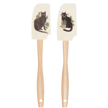 Set of 2 Black Cat Spatulas featuring black cats next to plants on a cream background, perfect for cooking and baking.