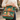 Person holding a green tote bag with owl design outdoors