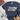 A navy blue heather graphic t-shirt with the words 'books & cats' printed in white script, styled in a flat-lay with white sneakers and denim shorts on a white background.