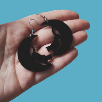 Handcrafted lightweight earrings with hypoallergenic stainless steel hardware, showcasing a black cat against a black moon.