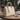 Beige handbag with a decorative charm on a wooden table outdoors