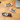 Three cat-shaped cable organizers on a wooden surface with electronic devices.