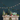 Decorative Christmas mantel with trees, presents, and a garland against a dark blue wall.
