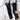 A pair of black cat-face long gloves hanging on a metal wall rack, with a hand holding one glove to show its flexibility. The background is a clean white tiled wall with a gold-framed mirror and a glass pump bottle.
