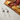 Two cat-shaped cheese knives on a white surface with a charcuterie board in the background.