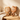 Two wooden hairbrushes with cat and fan-shaped handles, shown on a light wood surface against a warm beige wall with soft sunlight and shadows.