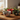 Four Christmas-themed ceramic bowls arranged on a wooden table near a window, decorated with festive holiday illustrations including stockings, candy canes, snowman, and ornaments. Warm fairy lights and a mug are softly blurred in the background.