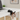 Black cat-shaped phone holder on a white desk with a laptop and a bag.