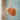 An orange cat-shaped bath sponge hanging from a white rope, covered in water droplets against a light blue tiled background.