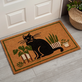 Black cat playing with a ball of wool beside potted plants on Flower Cat Doormat.