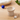 Beige ceramic cat toy on a wooden surface with a blue ball and a small mouse-shaped toy.