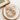 Beige fluffy scrunchie on a white plate with a wooden coaster underneath