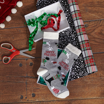 Close-up of Happy Pawlidays Socks with festive cats in sweaters and paw print design on gray fabric.