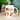 White mug with cat illustrations and text on a wooden surface with plants in the background