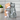 Two ceramic cat figurines, one orange and one gray, hugging each other on a white background.