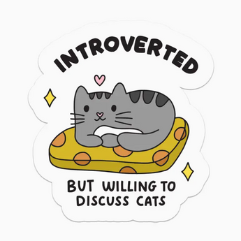 A grey tabby cat lounging on a cozy cat bed, looking content. Above the cat, the words "Introverted But Willing To Discuss Cats" are written in a playful font.