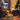 Candle with a cat figurine on a table with wine glasses and a Christmas tree in the background