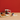 Red mug with cat designs on a wooden table against a red wall.