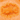 An orange fish-shaped bath bomb resting on orange-colored foam.