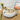 Cat lying on a round woven pet bed with flowers and a picture frame in the background