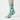 A pair of light blue crew socks with a whimsical pattern of cartoon cats in cowboy hats, cacti, and pink cowboy boots, displayed against a plain white background.