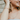 Woman wearing a rose gold necklace and bracelet with a blurred background