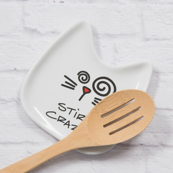 "Stir Crazy" cat face spoon rest with spiral eyes and text, displayed on kitchen counter.