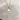 A gold cat-shaped pendant necklace with a white pearl inlay and a dangling white pearl, shown on a light gray textured background.