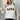 Person wearing a cream sweatshirt with black cat illustrations in festive hats and scarves.