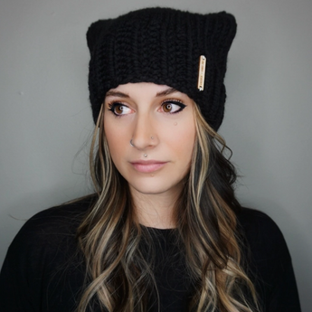 Woman wearing a stylish cat ear beanie outdoors, keeping warm in winter.