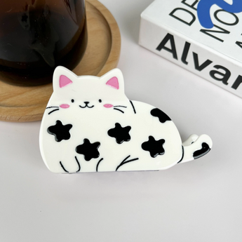 White cat hair claw with black spots, smiling expression, made of durable plastic and metal.