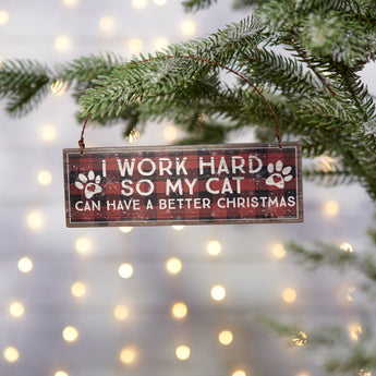 Wooden ornament with the message "I Work Hard So My Cat Can Have A Better Christmas," featuring a rustic pet-themed design and a twisted metal wire for hanging.