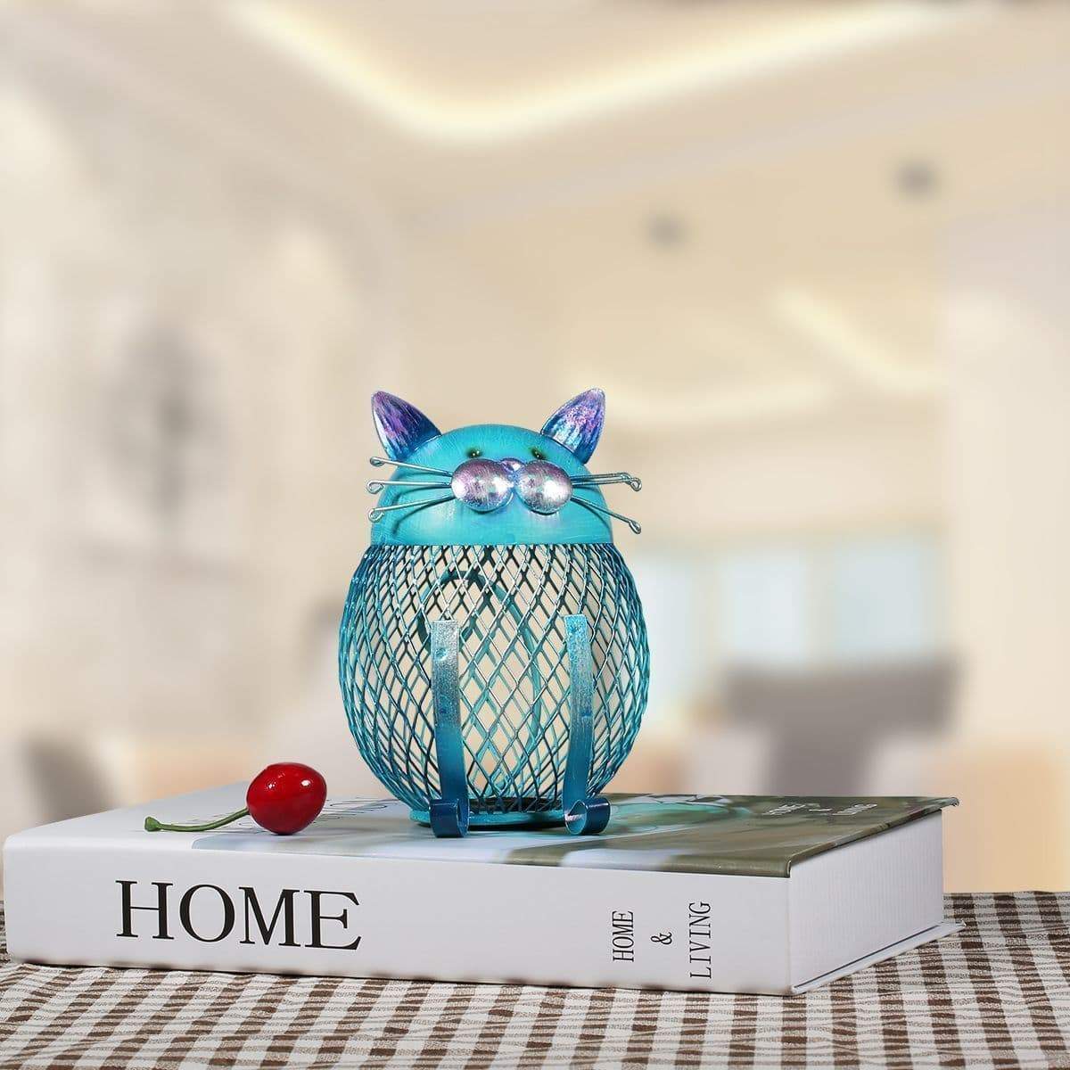 This unique metal kitty bank is painted in a vibrant blue color that stands out and gives your space an artistic touch.