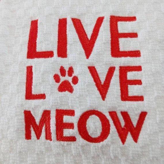 Cat kitchen towel decorated with the text Live Love Meow hand embroidered in red